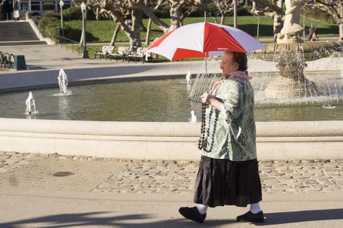 Old woman walking by a fountain